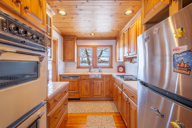 kitchen featuring wall oven, crown molding, tile counters, wood ceiling, and freestanding refrigerator