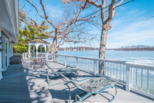 wooden terrace featuring outdoor dining space, a gazebo, and a water view