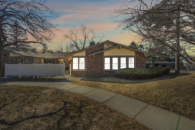 view of front facade featuring brick siding, a front lawn, and fence