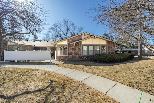 view of front of home with brick siding, a front yard, and fence