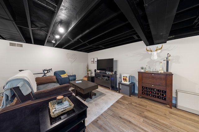 living room featuring radiator heating unit, wood finished floors, and visible vents