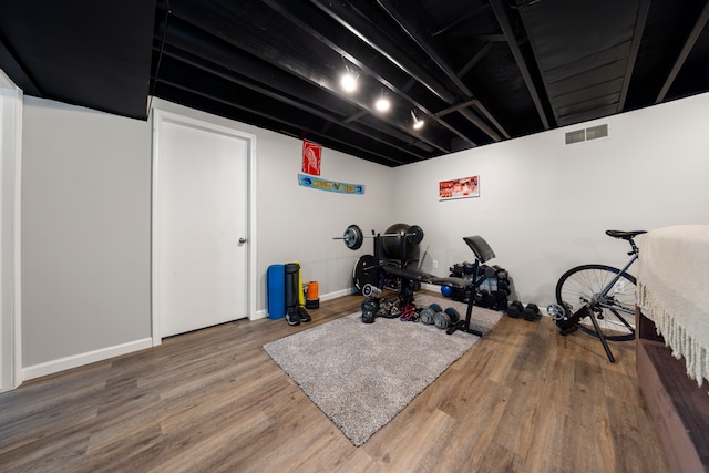 workout room with wood finished floors, visible vents, and baseboards