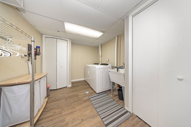 clothes washing area with washer and dryer, a sink, laundry area, and light wood finished floors