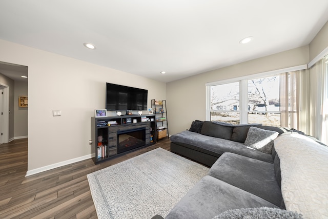 living room featuring recessed lighting, baseboards, wood finished floors, and a glass covered fireplace