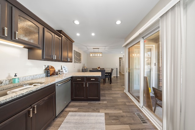 kitchen featuring dishwasher, a peninsula, dark brown cabinets, and visible vents