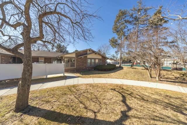 view of front of home featuring brick siding, a front yard, and fence