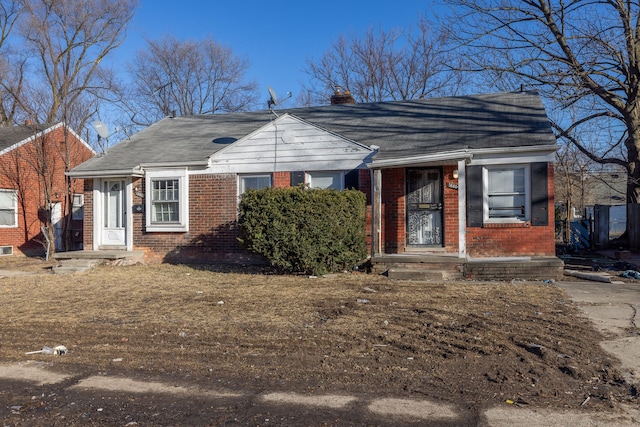 bungalow-style home with brick siding and a chimney