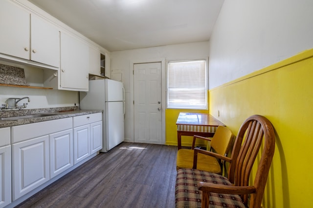 kitchen with white cabinetry, dark wood-style floors, freestanding refrigerator, and a sink