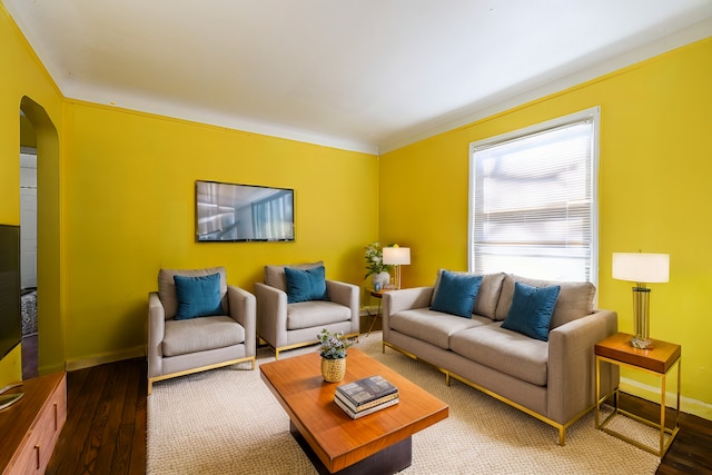 living room featuring arched walkways, baseboards, and wood finished floors