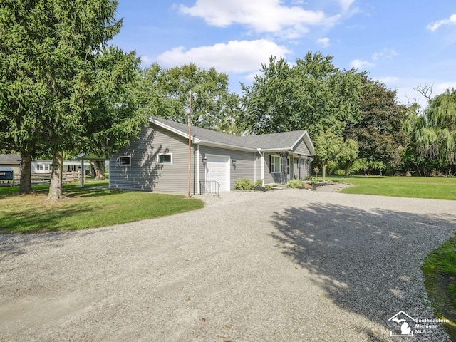 ranch-style house featuring a garage, gravel driveway, and a front yard