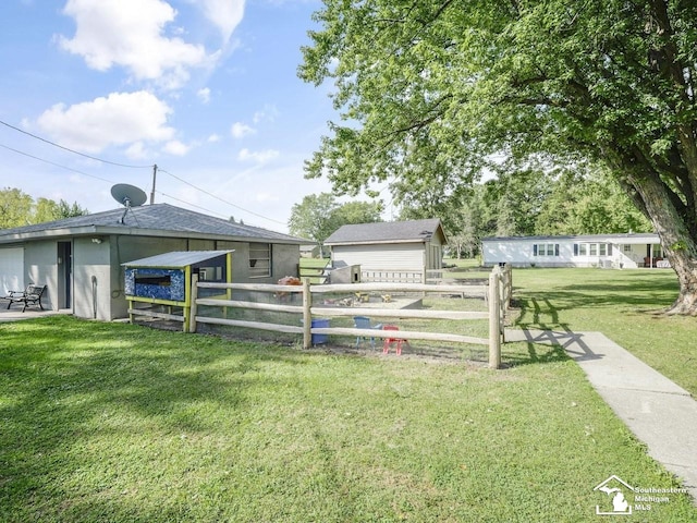 exterior space featuring an outdoor structure, fence, and a lawn