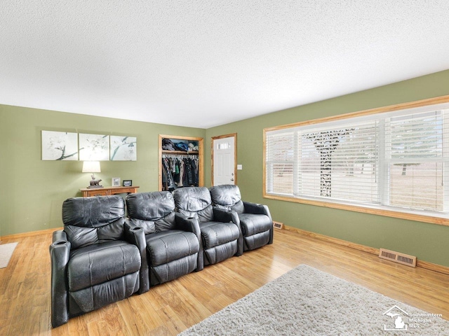 living room with a wealth of natural light, visible vents, and wood finished floors