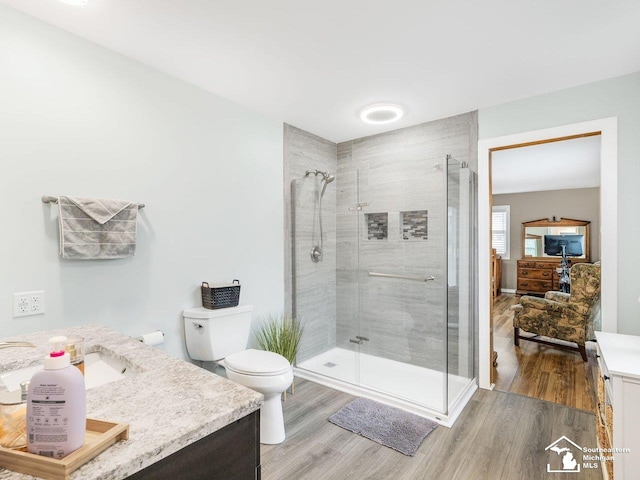 bathroom featuring a shower stall, toilet, vanity, and wood finished floors