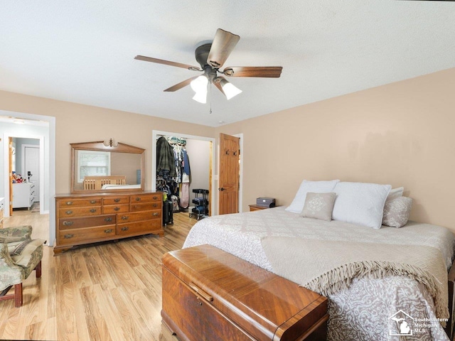 bedroom featuring ceiling fan, a closet, light wood-style flooring, and a spacious closet