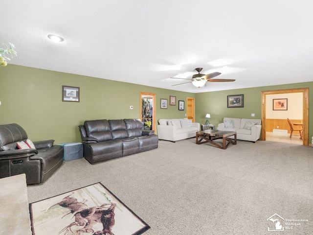 carpeted living area with a textured ceiling and ceiling fan