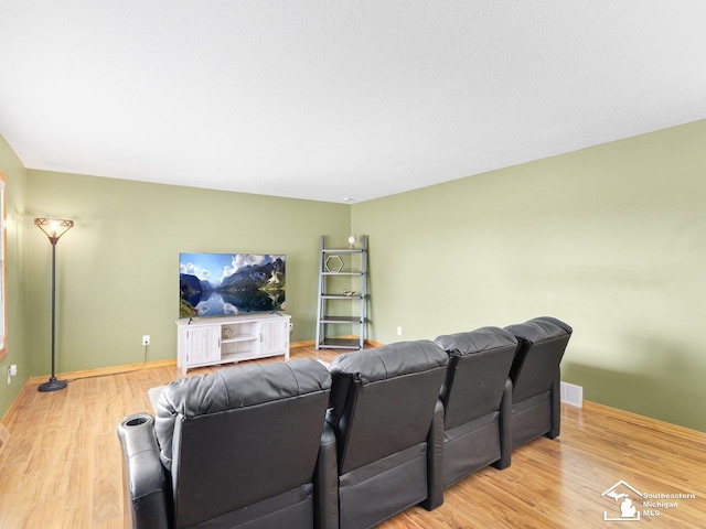 cinema room with visible vents, baseboards, and wood finished floors