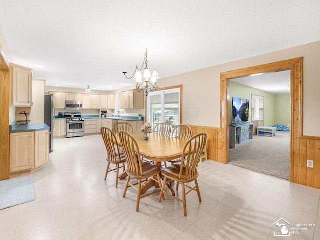 dining area with wooden walls, an inviting chandelier, and a wainscoted wall