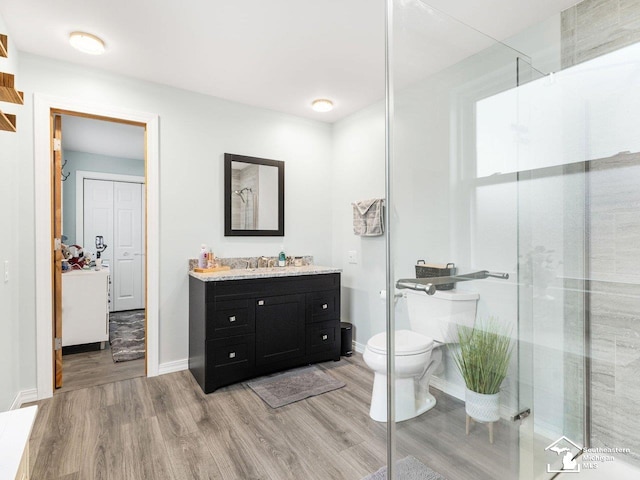 full bathroom with a shower stall, toilet, vanity, and wood finished floors