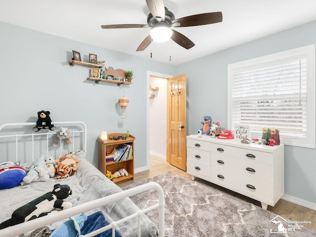 bedroom featuring baseboards, light wood finished floors, and ceiling fan