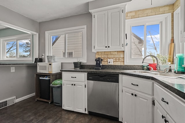 kitchen featuring white microwave, dark countertops, dishwasher, white cabinets, and a sink