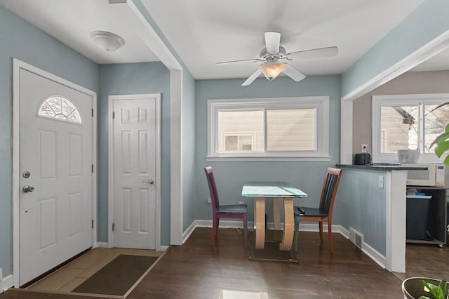 foyer entrance with a ceiling fan, wood finished floors, visible vents, and baseboards