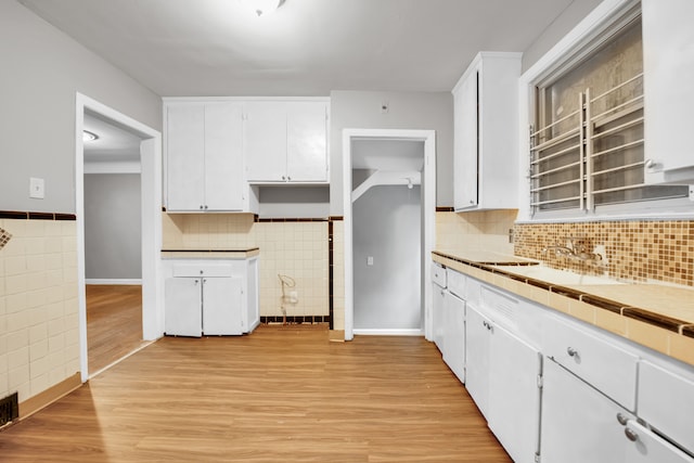 5984 Courville St, Detroit, MI 48224 - kitchen with a sink, tile walls, white cabinets, and light wood finished floors