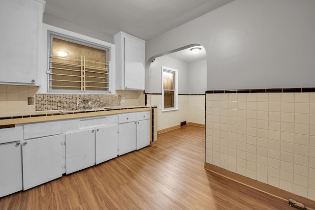 5984 Courville St, Detroit, MI 48224 - kitchen featuring tile walls, tile counters, light wood-style floors, white cabinetry, and a sink