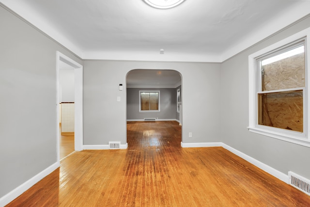 5984 Courville St, Detroit, MI 48224 - empty room with arched walkways, visible vents, baseboards, and wood-type flooring