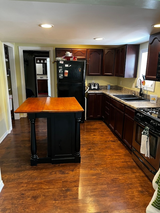 kitchen featuring a sink, dark wood finished floors, freestanding refrigerator, dark brown cabinets, and stainless steel gas range