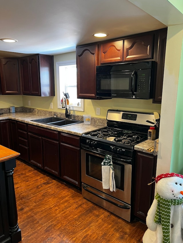 kitchen featuring dark wood-style floors, stainless steel range with gas stovetop, black microwave, and a sink