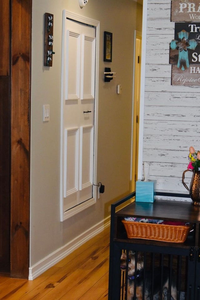 interior space with baseboards, light wood-style flooring, and wood walls