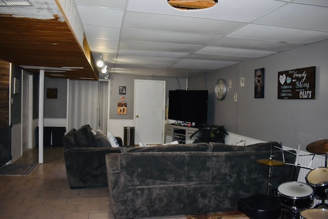 living area featuring a drop ceiling and tile patterned flooring