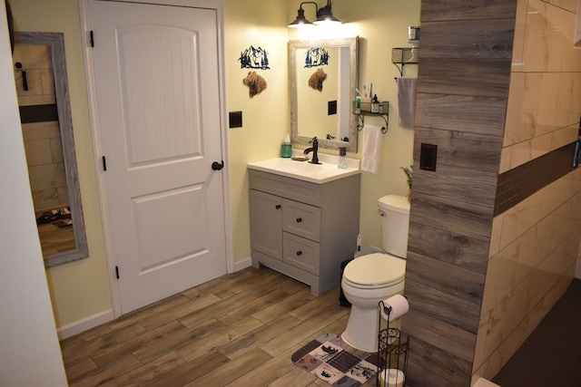 bathroom featuring baseboards, vanity, toilet, and wood tiled floor