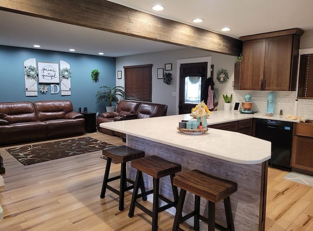 kitchen featuring a breakfast bar area, a peninsula, light countertops, light wood-style floors, and dishwasher