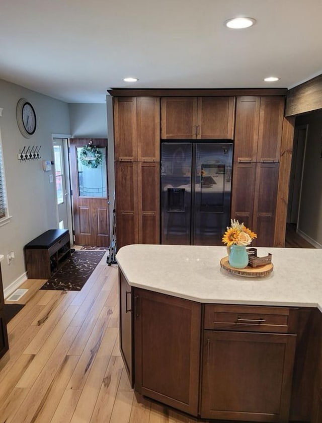 kitchen with light wood finished floors, baseboards, light countertops, recessed lighting, and black fridge with ice dispenser