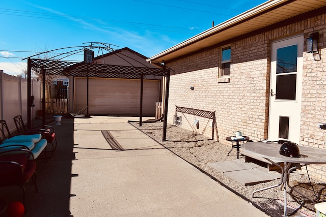 view of patio featuring an outbuilding, concrete driveway, a garage, and fence