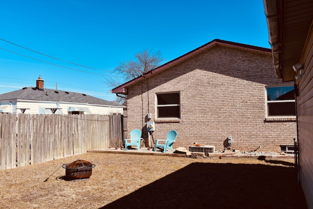 exterior space with cooling unit, fence, brick siding, and an outdoor fire pit