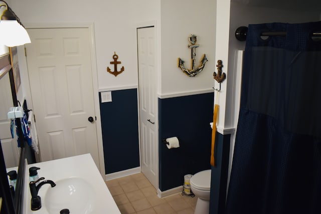 bathroom featuring a sink, toilet, a shower with shower curtain, and tile patterned flooring