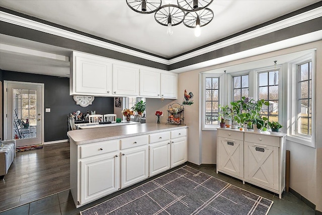 kitchen featuring baseboards, a peninsula, white cabinets, and light countertops