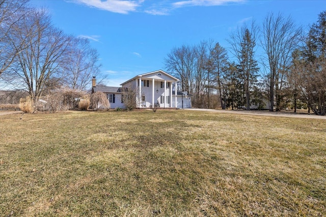 greek revival inspired property with a chimney and a front lawn