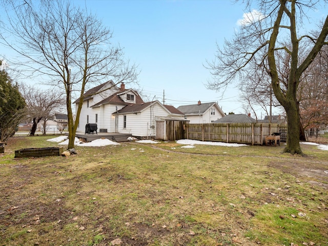 rear view of house with a yard, a deck, and fence