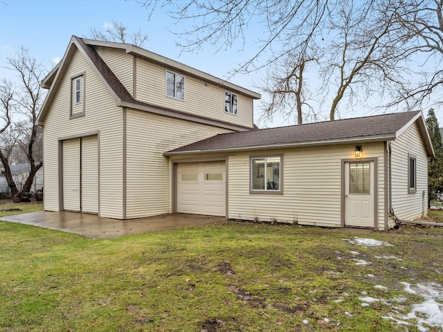 back of property featuring a yard, a garage, driveway, and roof with shingles