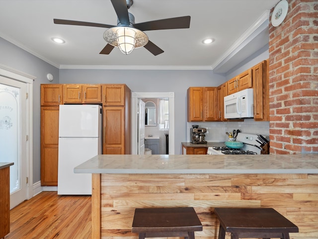 kitchen featuring light wood finished floors, backsplash, ornamental molding, a peninsula, and white appliances