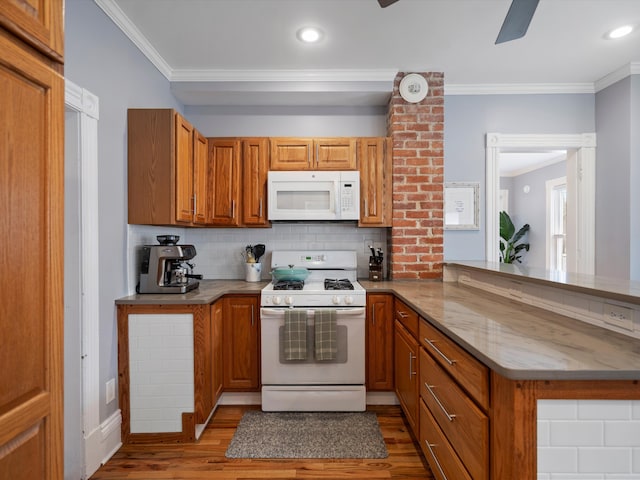 kitchen with ornamental molding, a peninsula, wood finished floors, brown cabinetry, and white appliances