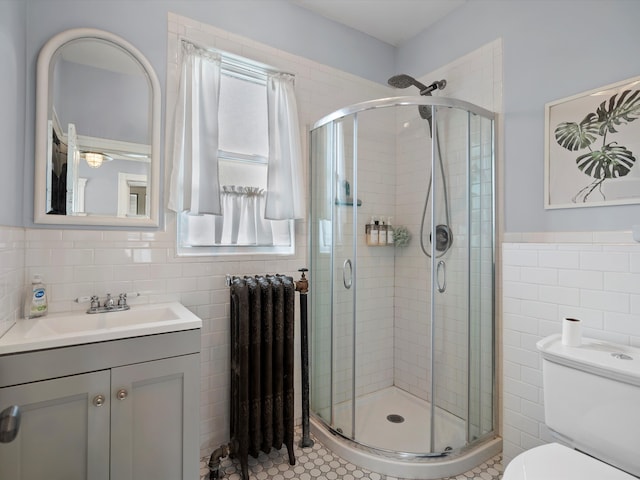 full bathroom with a shower stall, tile walls, toilet, radiator heating unit, and vanity