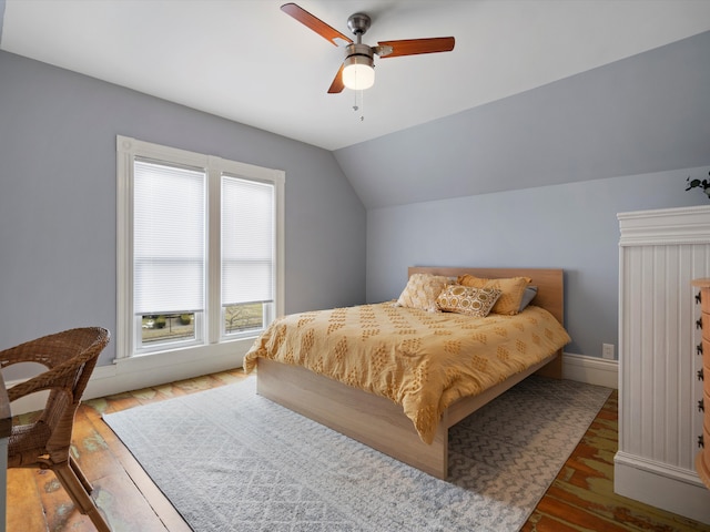 bedroom with lofted ceiling, wood finished floors, baseboards, and ceiling fan