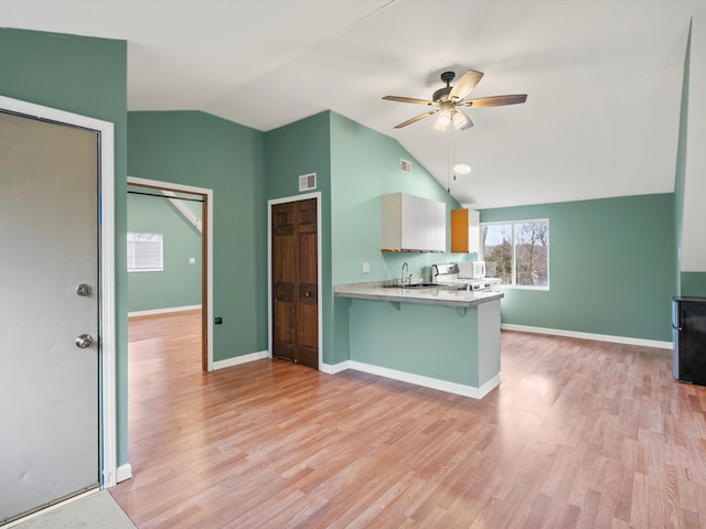 kitchen featuring a sink, a peninsula, ceiling fan, and light wood finished floors