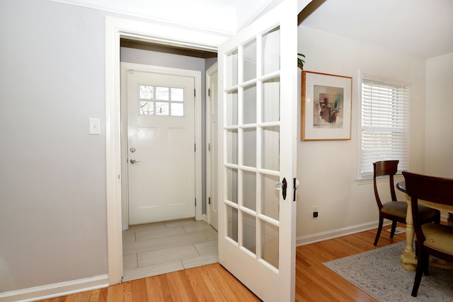 doorway to outside featuring baseboards and light wood-style floors