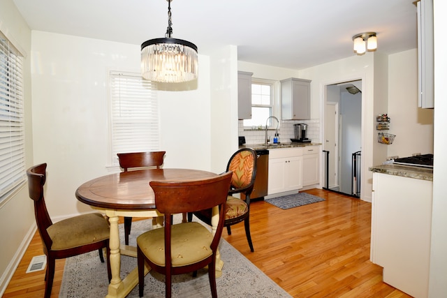 dining space with visible vents, baseboards, light wood-style flooring, and a chandelier