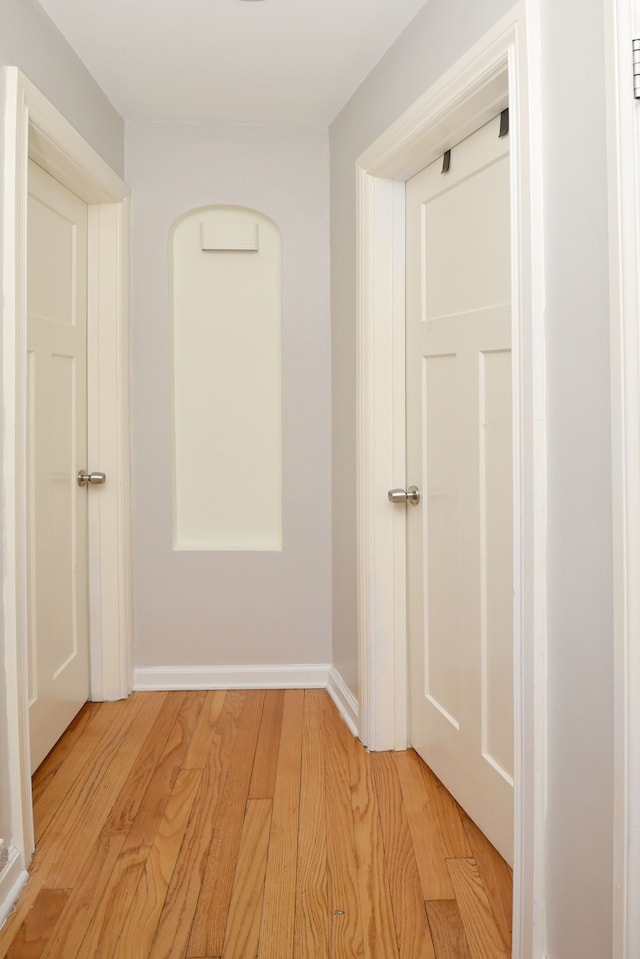 hallway with light wood-type flooring and baseboards